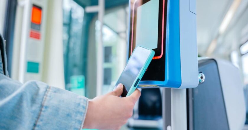 Passenger uses smartphone to tag on with contactless payment at a public transport validator in Perth, part of the city’s contactless transport payments trial.