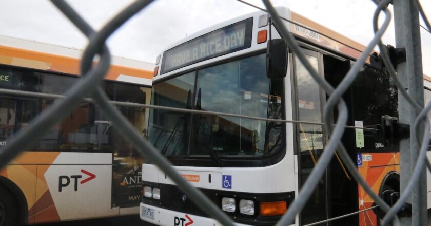 CDC Victoria buses parked behind a fence in Melbourne during industrial action, with one bus displaying “Have a Nice Day” on its destination board.